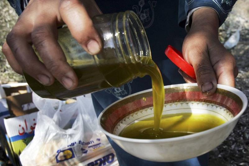 A woman pours olive oil into a bowl. 