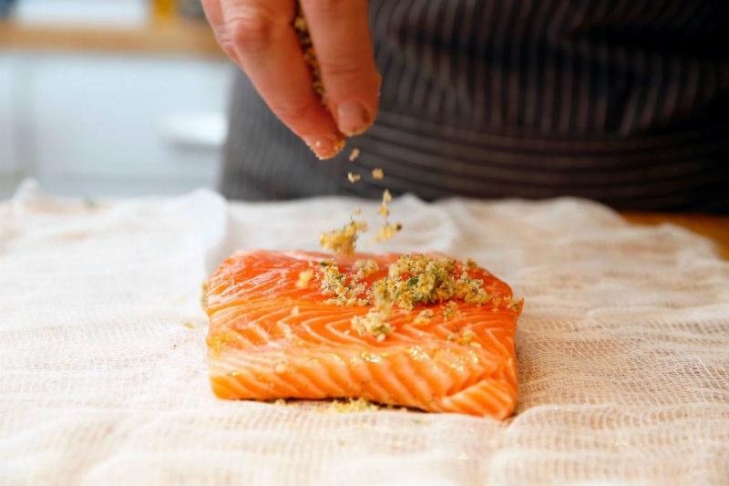salmon 1076548116 someone sprinkling bread crumbs on a piece of raw salmon