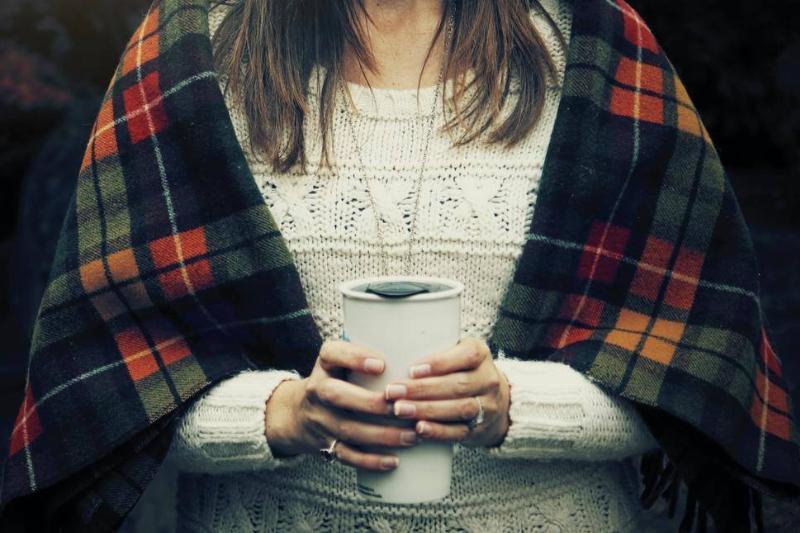 travel mug A woman holds a white travel mug.