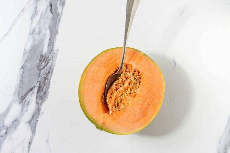 cantaloupe 1134234484 Half of ripe organic Cantaloupe melon with seeds and spoon inside