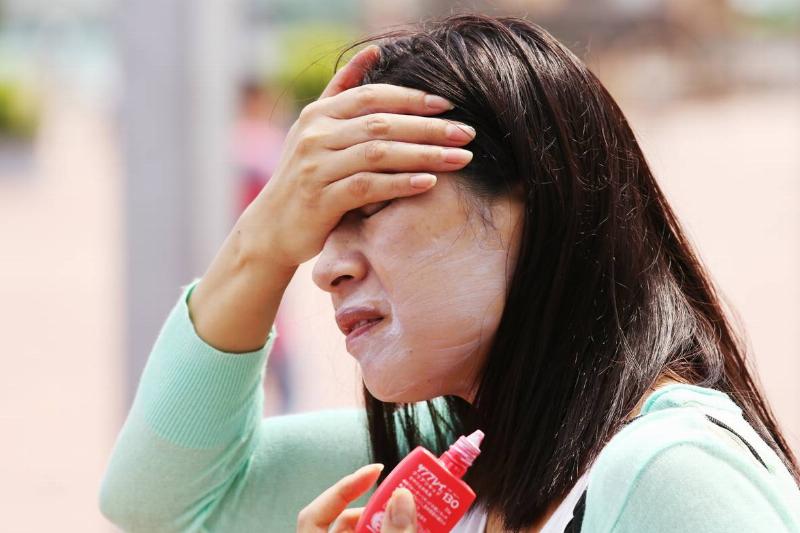 sunscreen-1095780948 A woman rubs sunscreen on her face.