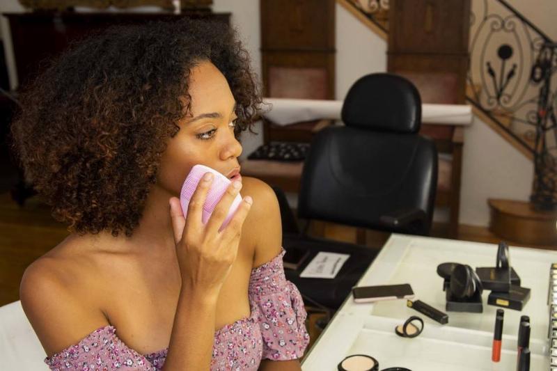 skin care-1163219599 A woman uses a skincare device to remove makeup.