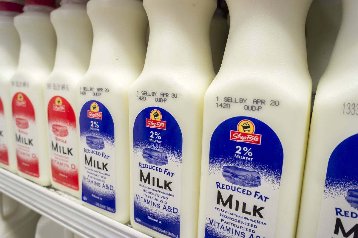 Reduced fat milk cartons are stacked on a grocery store shelf.