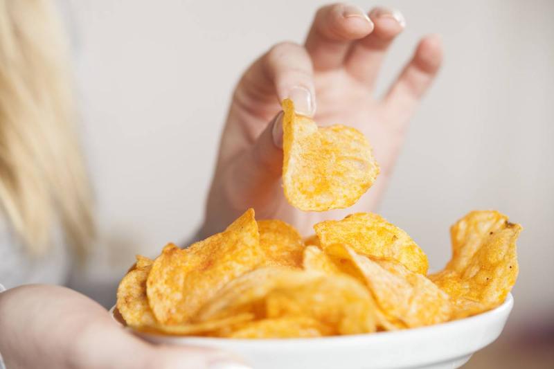 A woman eats potato chips.