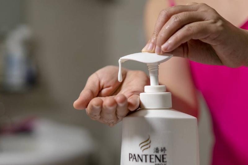 pouring shampoo - 836153156 A woman presses a shampoo bottle.