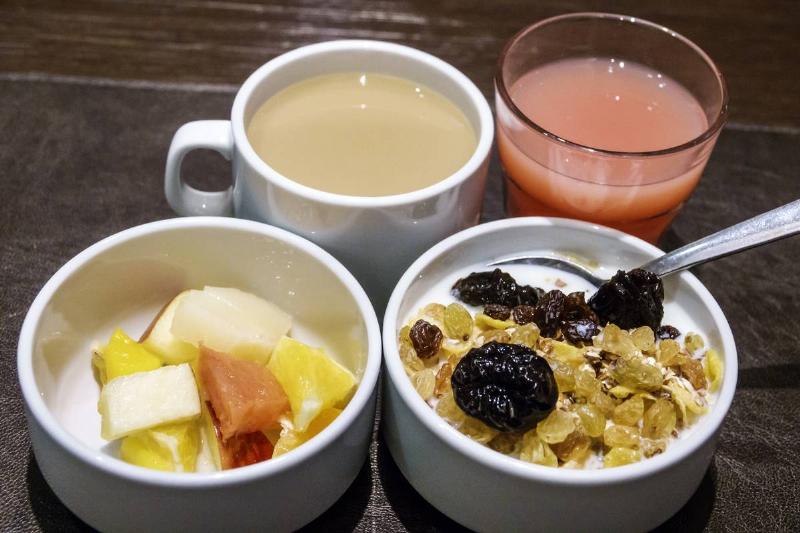 cereal - 982751114 Cereal is served with a bowl of fruit, coffee, and juice.