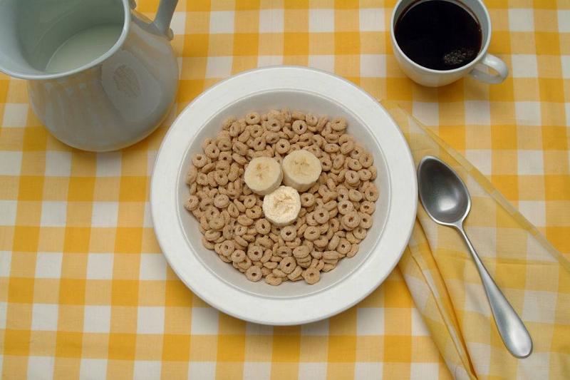 breakfast 90142930 View of a table setting with a bowl of breakfast cereal (and banana slices), a cup of coffee, and a pitcher of milk