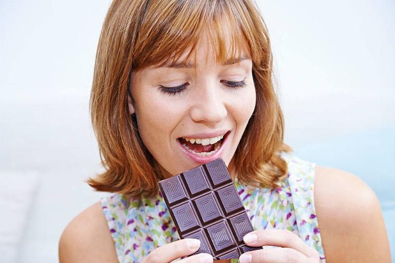 dark chocolate 586118998 Woman eating chocolate bar