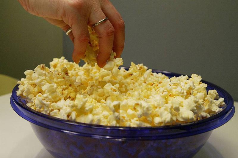 popcorn 3078932 A woman grabs freshly popped microwave popcorn from a bowl
