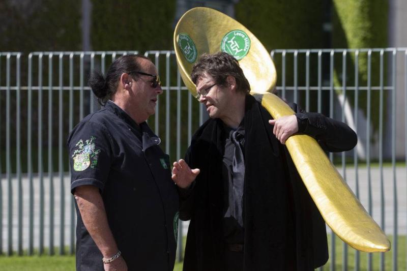 spoon 1213058217 men talking to each other with one holding a large gold spoon