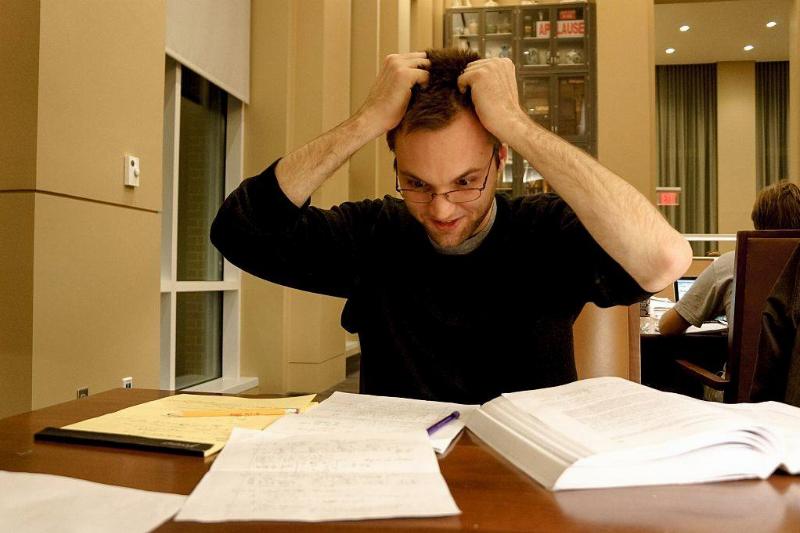 stress 586158318 A flustered college student grabs his hair as he looks at his notes