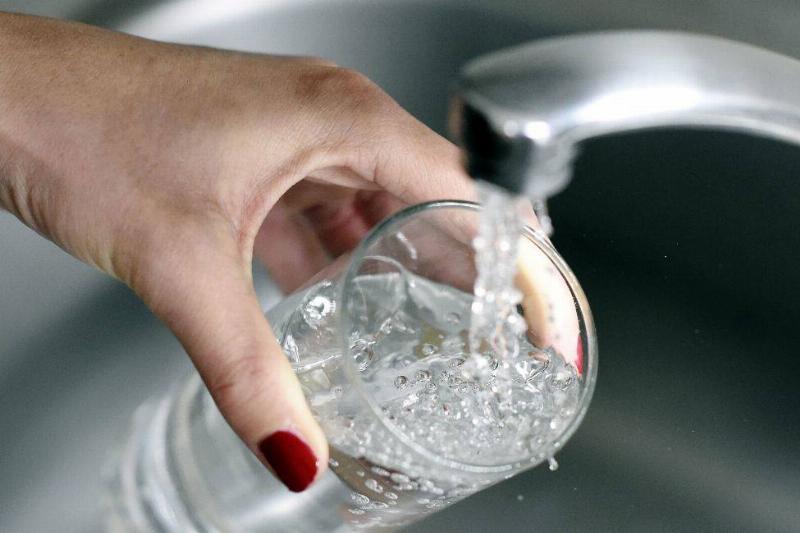 water 487150929 A woman fills up a glass with water