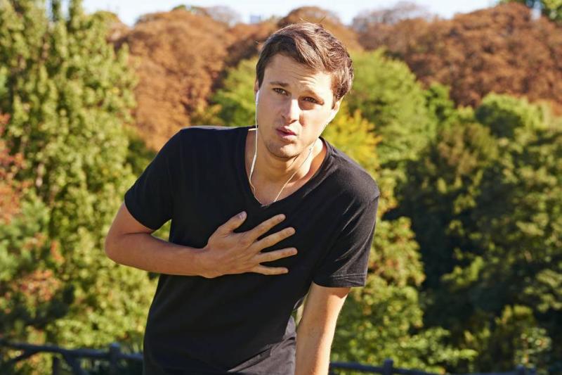 chest pain-586119674 A man clutches his chest in pain while on a hike.