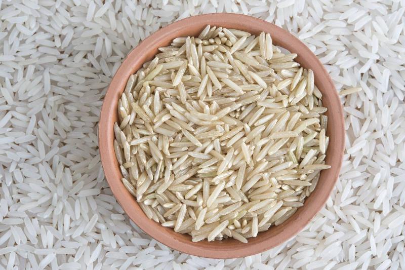 A bowl of brown rice sits on top of a pile of white rice.