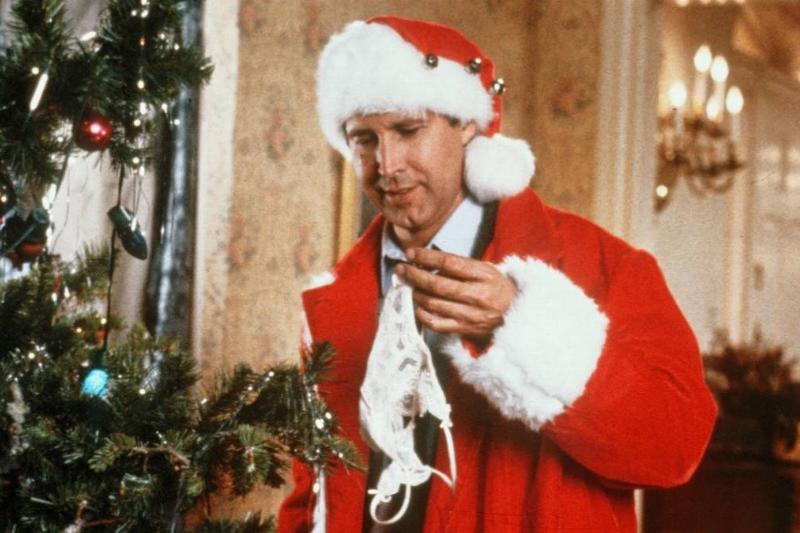 christmas outfit A still from Christmas Vacation shows a man dressed as santo looking at a gift.