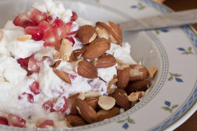 almonds in yogurt Almonds and pomegranate seeds are in a bowl of yogurt.