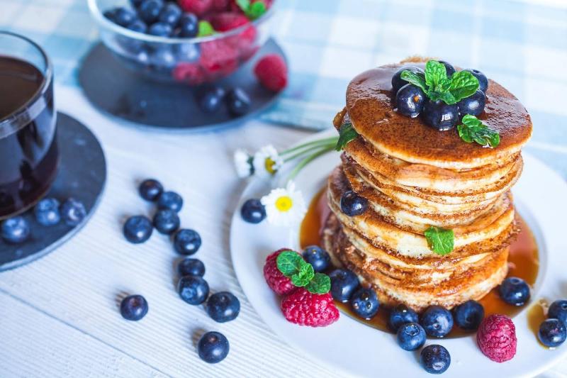 blueberry pancakes A large stack of blueberry pancakes is surrounded by blueberries.