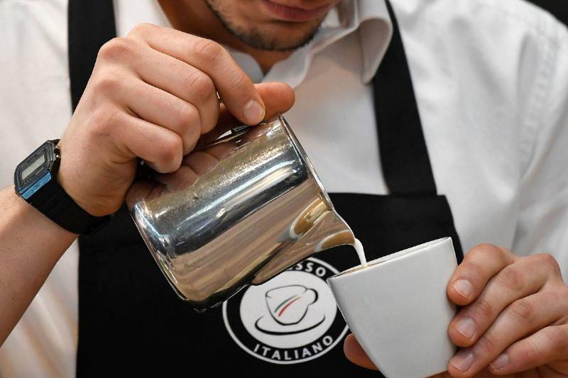 coffee cream-908328980 A barista pours cream into a coffee.