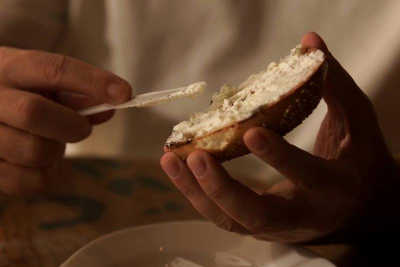 cream cheese A person spreads cream cheese on a bagel.