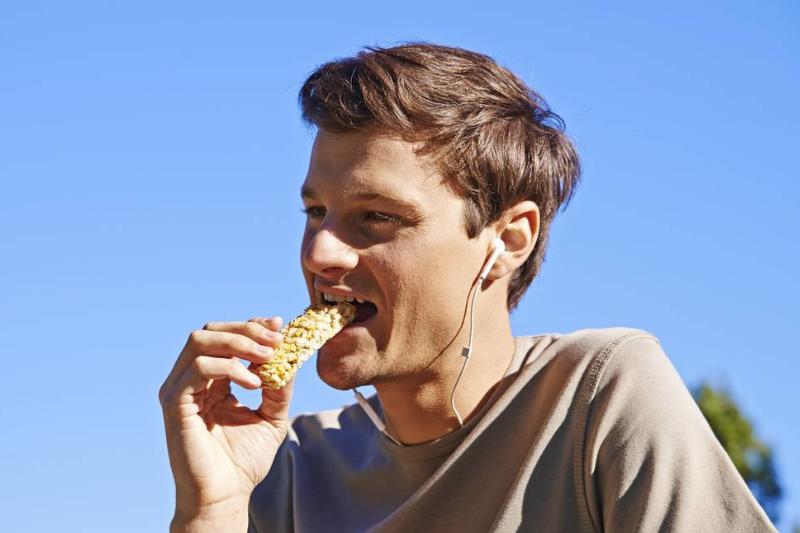 Man eating an energy bar A man eats a granola energy bar.