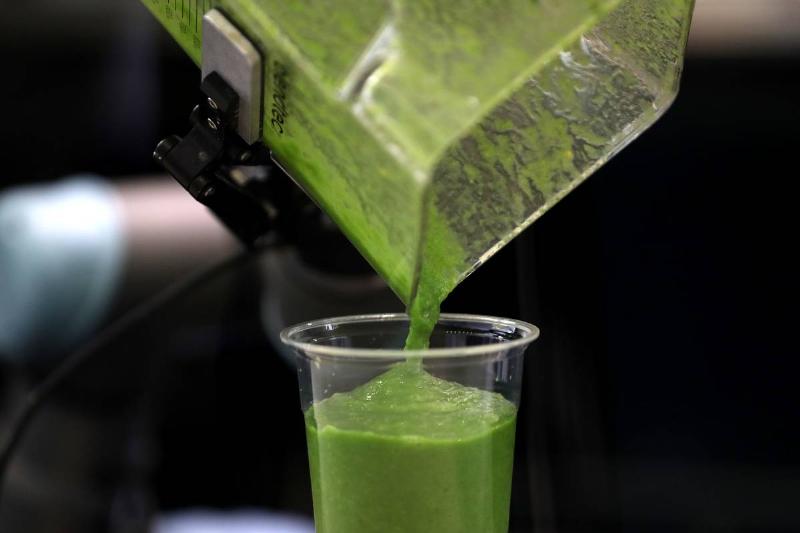 pouring smoothie A person pours a green smoothie into a glass.