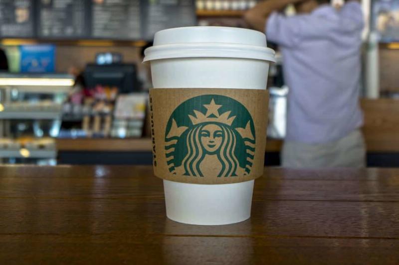 paper cup A to-go Starbucks cup is pictured on a table.