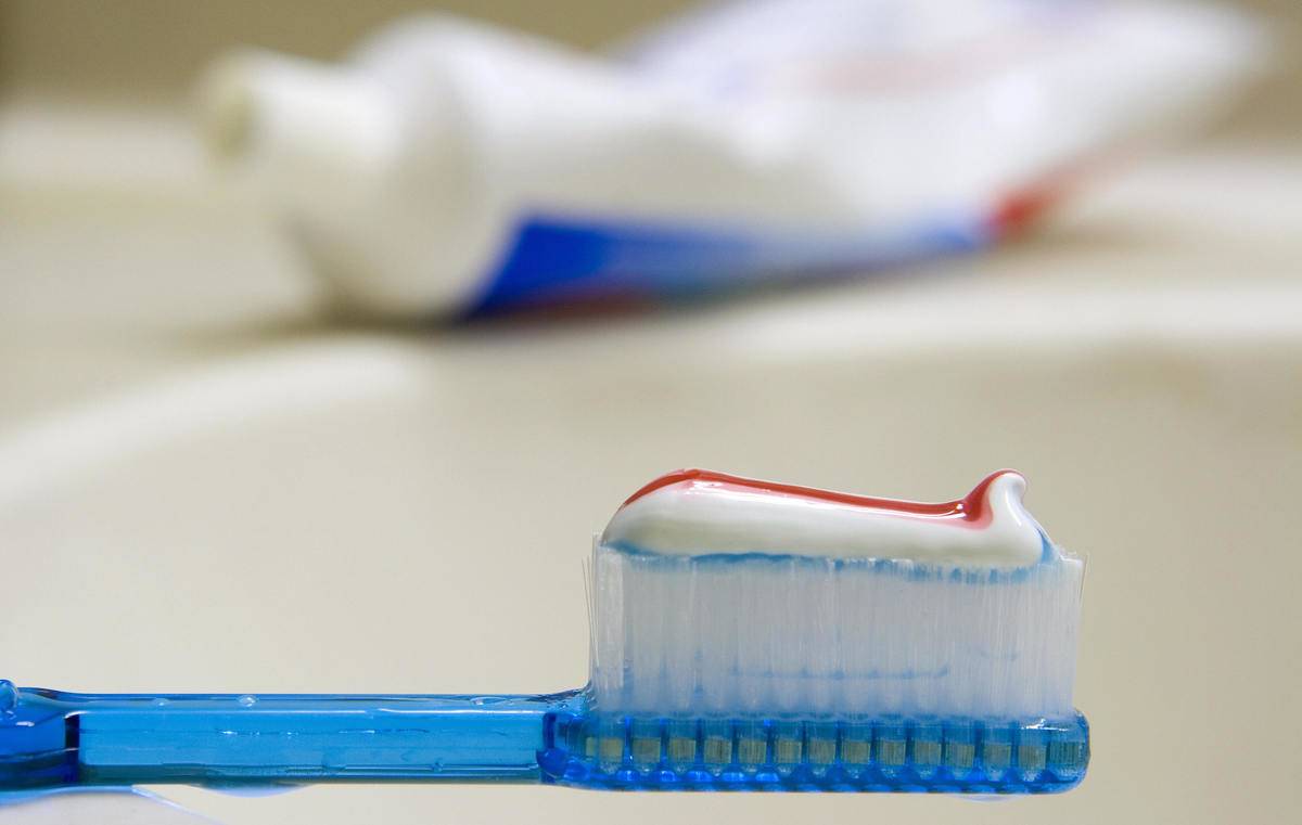 toothbrush A toothbrush is pictured with toothpaste on it in front of a sink.