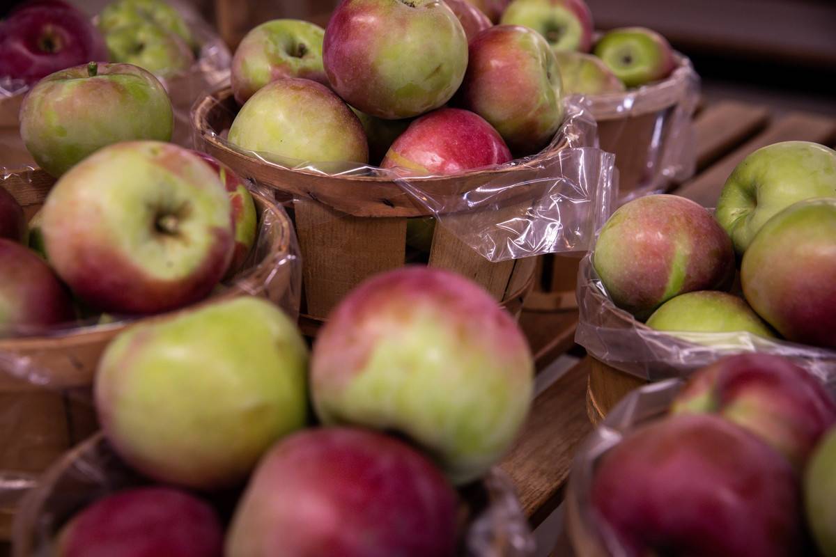 Apples are stored in baskets and plastic bags.