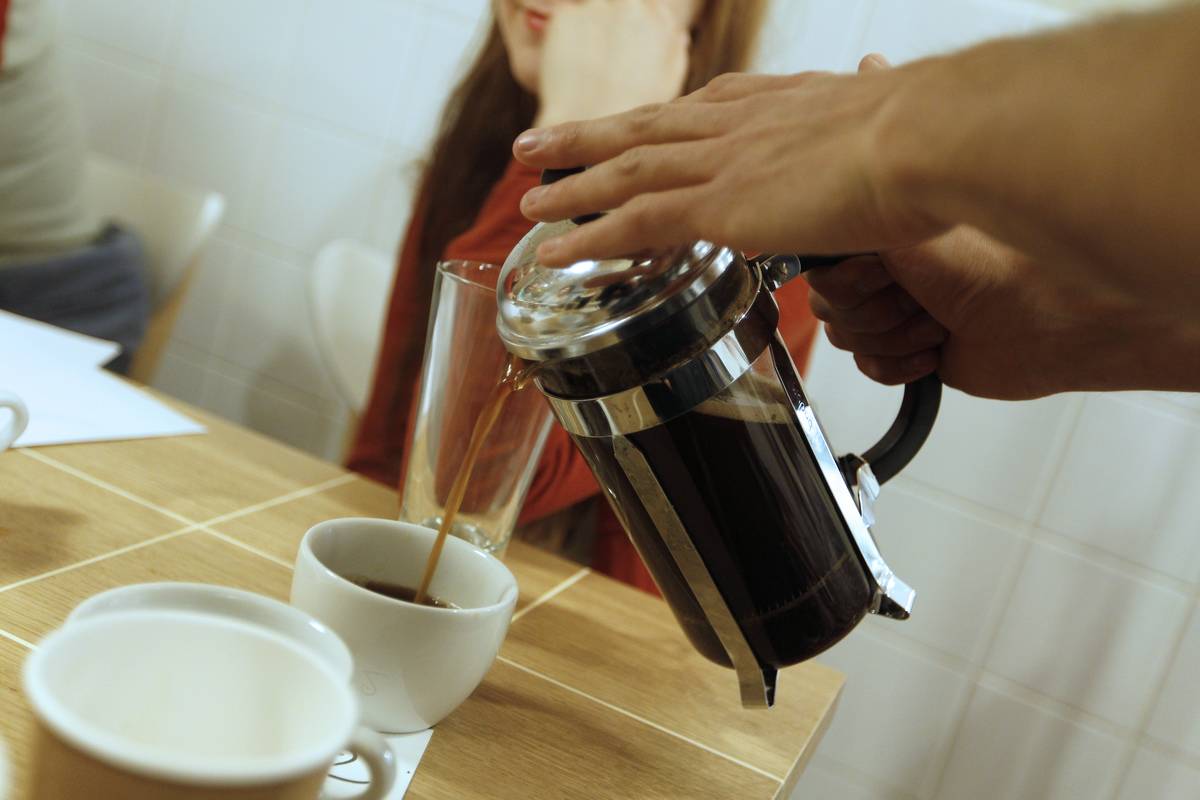 coffee pot A waiter pours hot coffee into a mug at a restaurant.