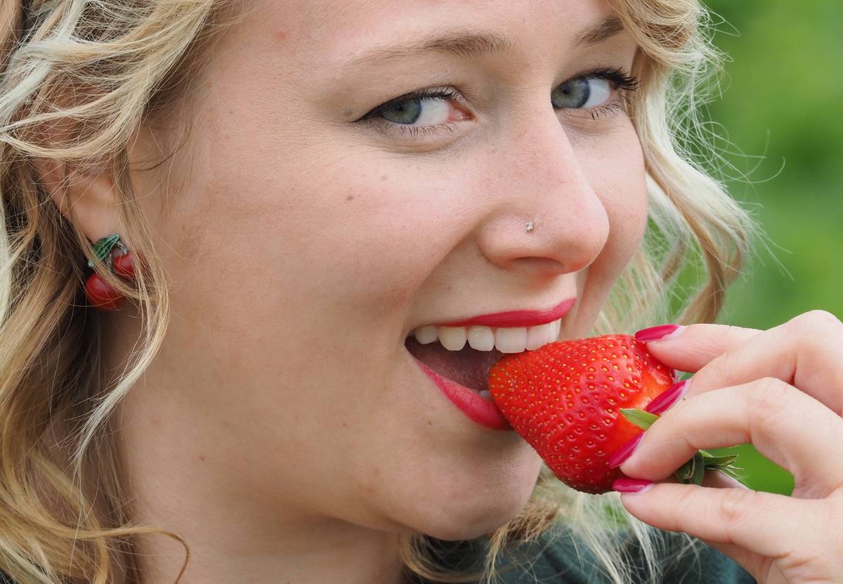 A woman eats a strawberry.