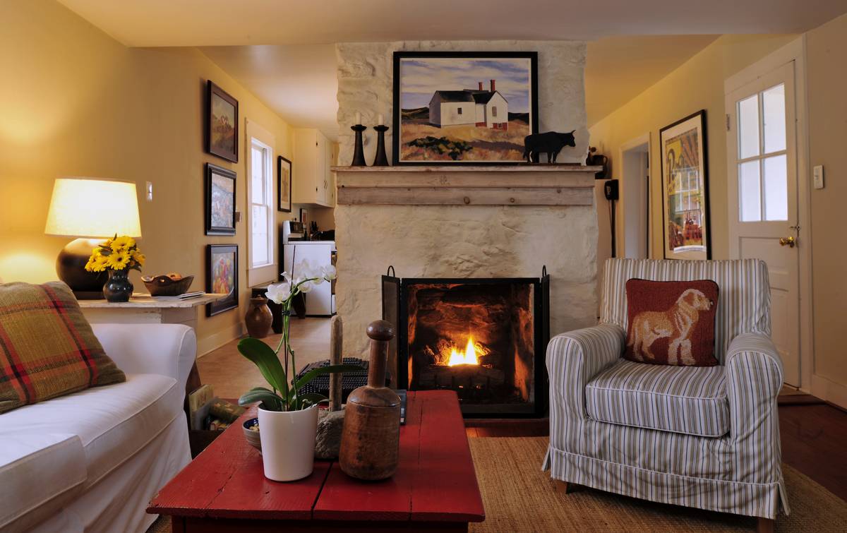 farmhouse decor A farmhouse has rural decor, like a fireplace, painting of a farmhouse, bull statue, and red coffee table.