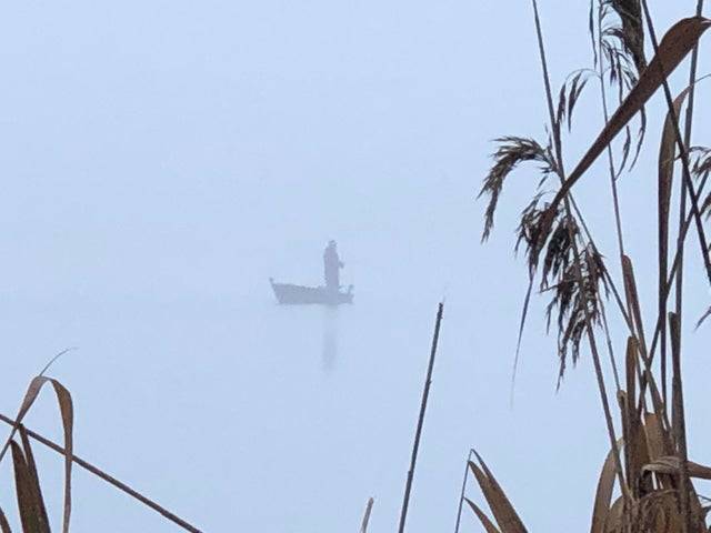 man fishing on foggy lake