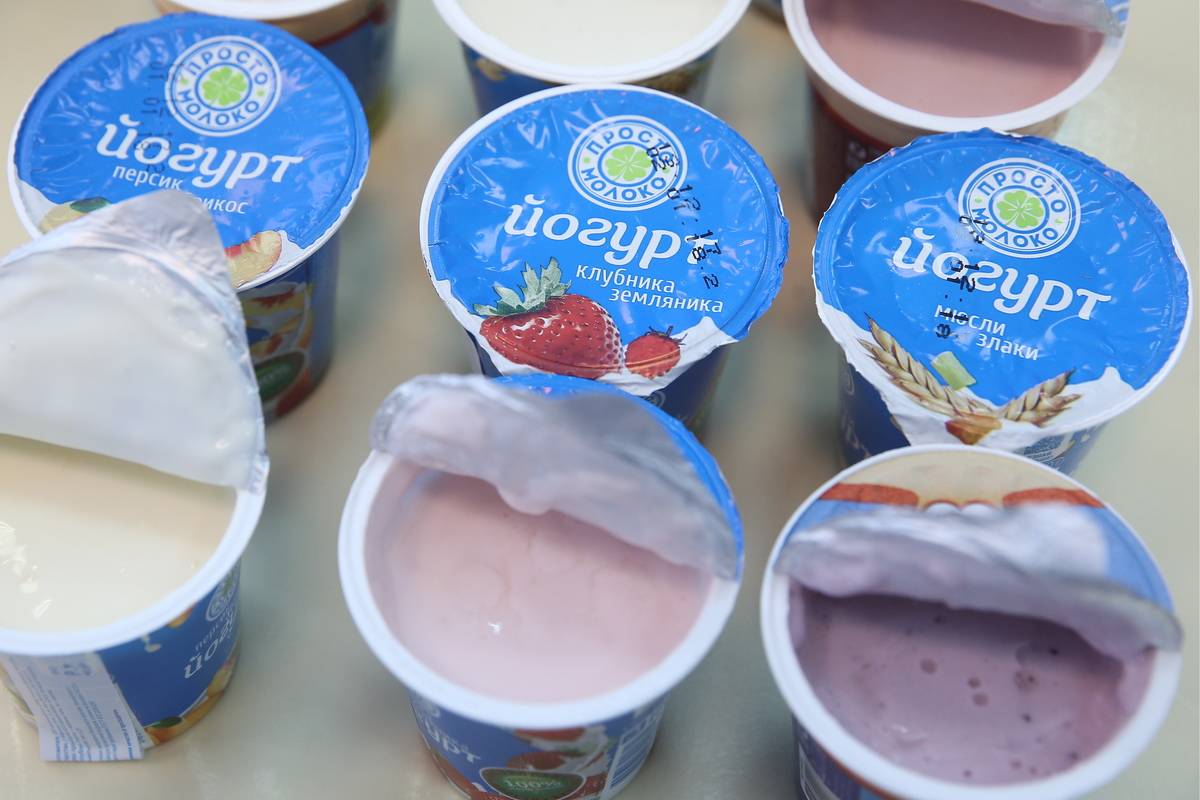 A variety of yogurt containers have their lids open.