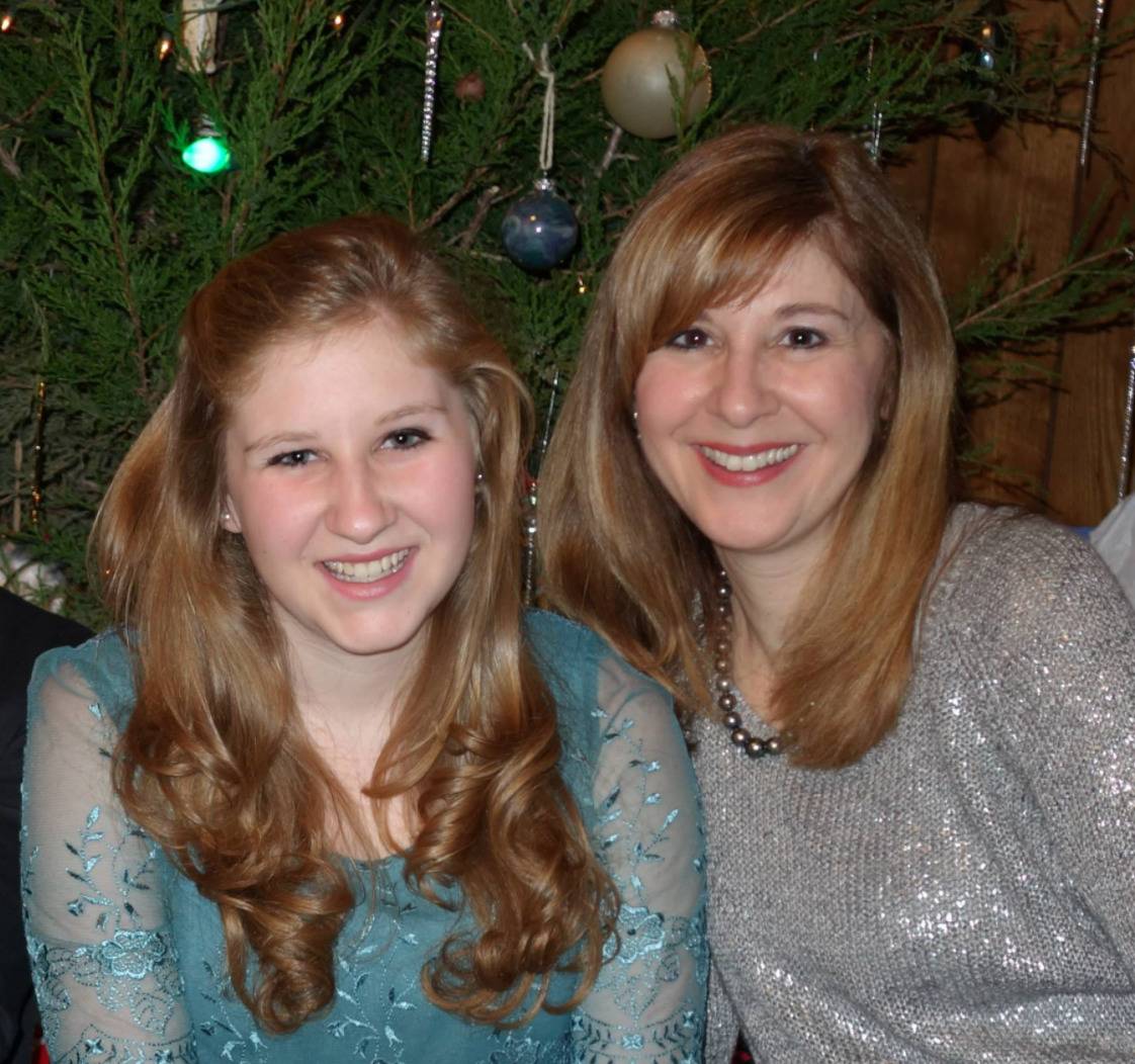 Rebecca takes a photo with her mother in front of a Christmas tree.