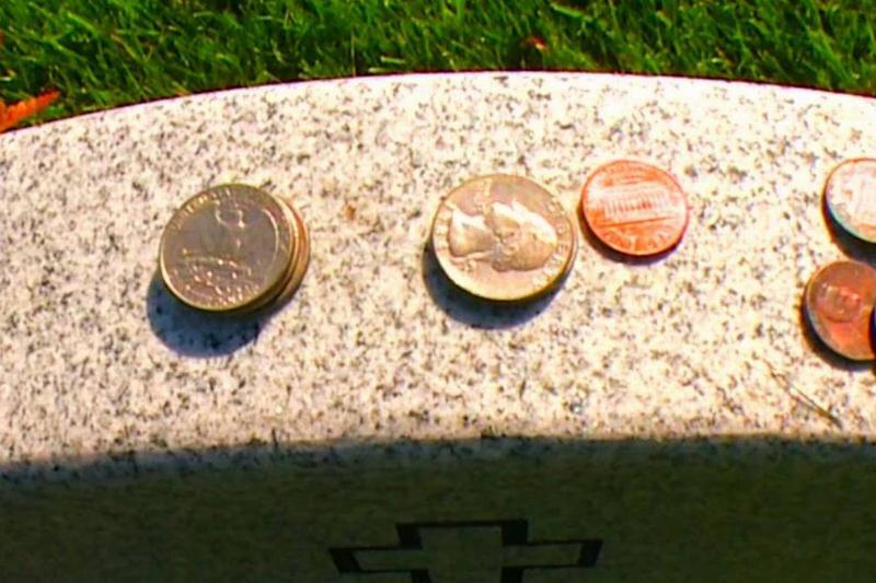A few American coins sit on top of a headstone.