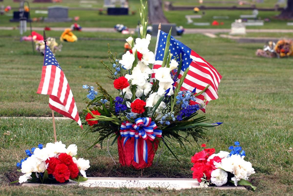 flags and flowers A bouquet is arranged with an American flag at a cemetery.