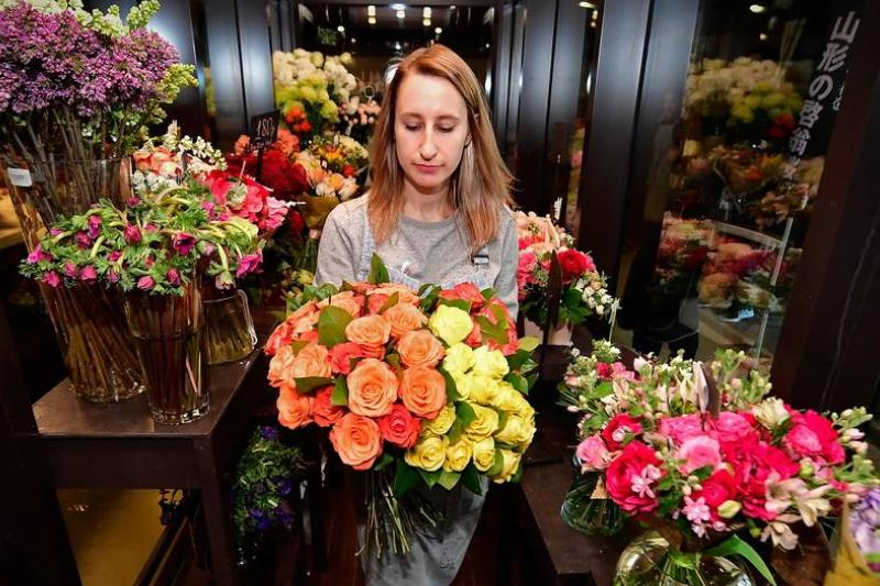 florist A florist carries a bouquet through her shop.