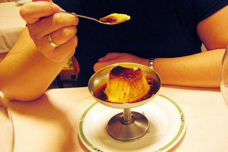 dessert 89416296 A woman eating a custard in a restaurant