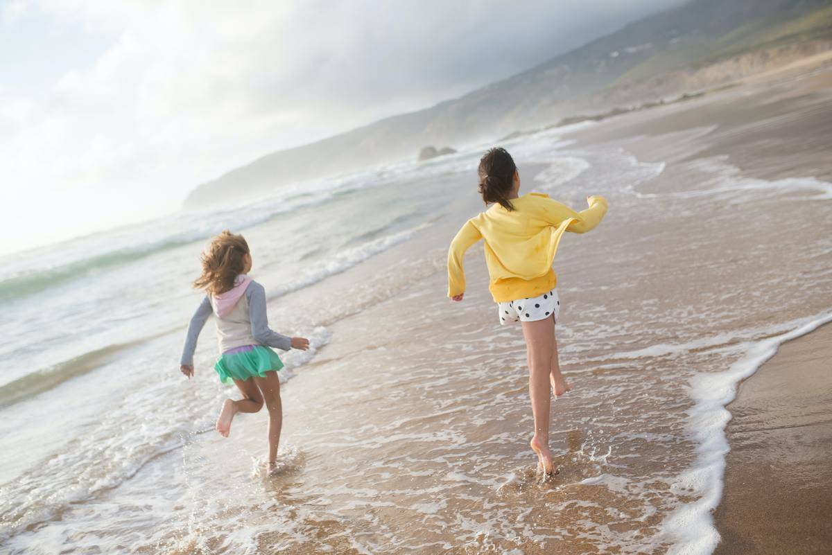 Beach Young girls run along cloudy beach