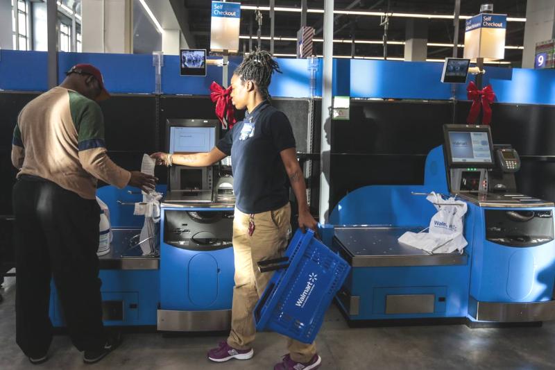 Self Checkout Woman working at Walmart monitors self-checkout kiosk