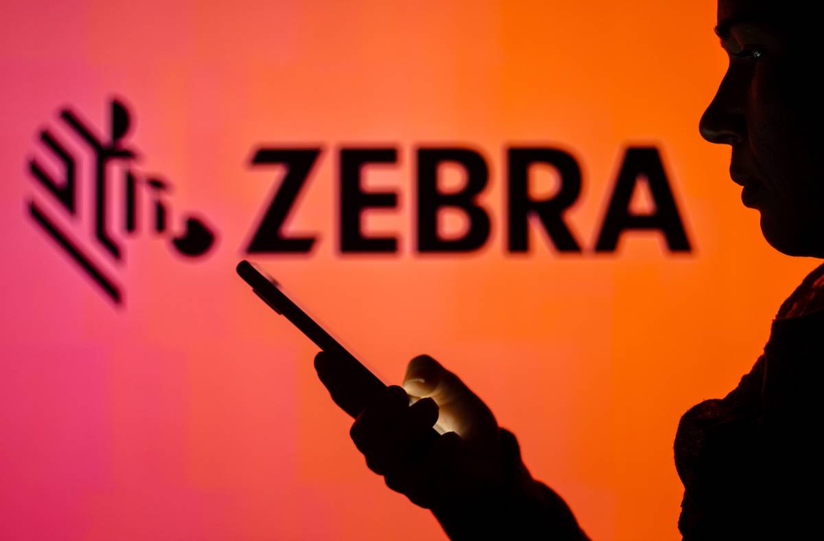 Zebra Technologies In this photo illustration, the Zebra Technologies logo is seen in the background of a silhouetted woman holding a mobile phone.