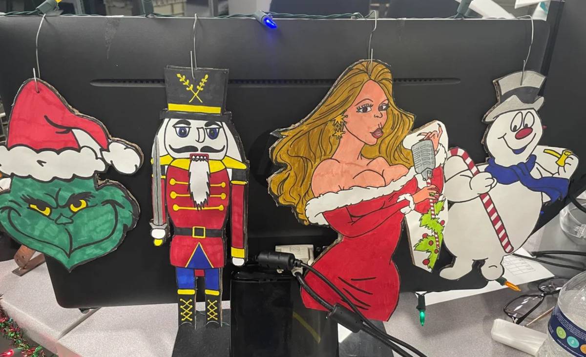 drawings of Grinch nutcracker, Mariah Carey and Frosty hanging from office computer