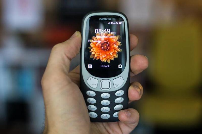 Man's hand holding old Nokia cell phone Man's hand holding old Nokia cell phone