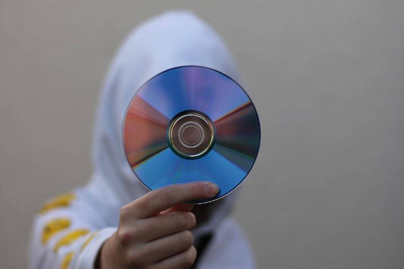 a person in a white hoodie holding a CD a person in a white hoodie holding a CD
