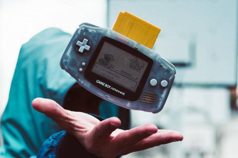 person in hooded jacket throwing up Game Boy Advance with Pokemon Yellow at basketball court person in hooded jacket throwing up Game Boy Advance with Pokemon Yellow at basketball court