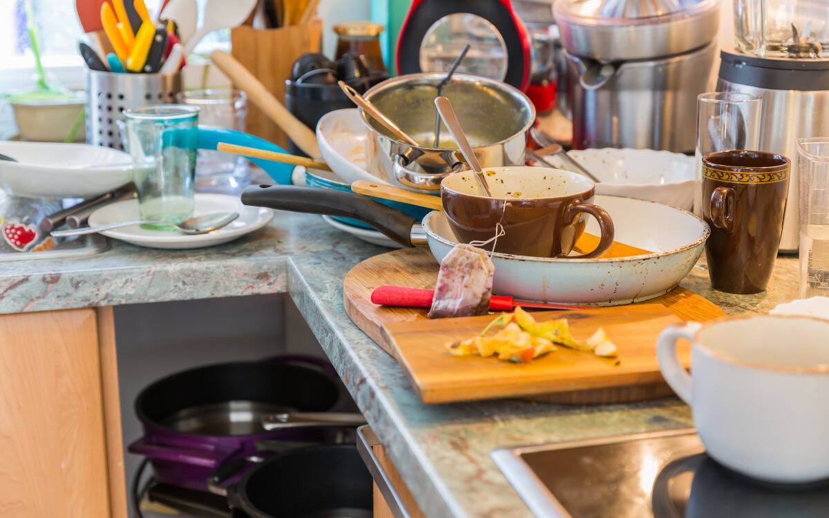 A kitchen sink and counter covered in dishes.