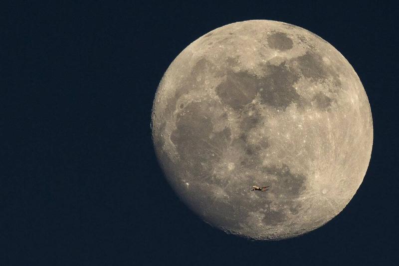 A Plane Is Dwarfed As It Flies Past The Moon A Plane Is Dwarfed As It Flies Past The Moon