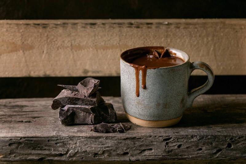 Ceramic cup of hot spicy homemade chocolate winter drink with chopped dark chocolate bar on old wooden shelf. Warm cozy drink Ceramic cup of hot spicy homemade chocolate winter drink with chopped dark chocolate bar on old wooden shelf. Warm cozy drink