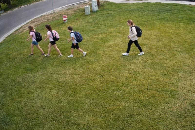 Four children walking across someone's front yard