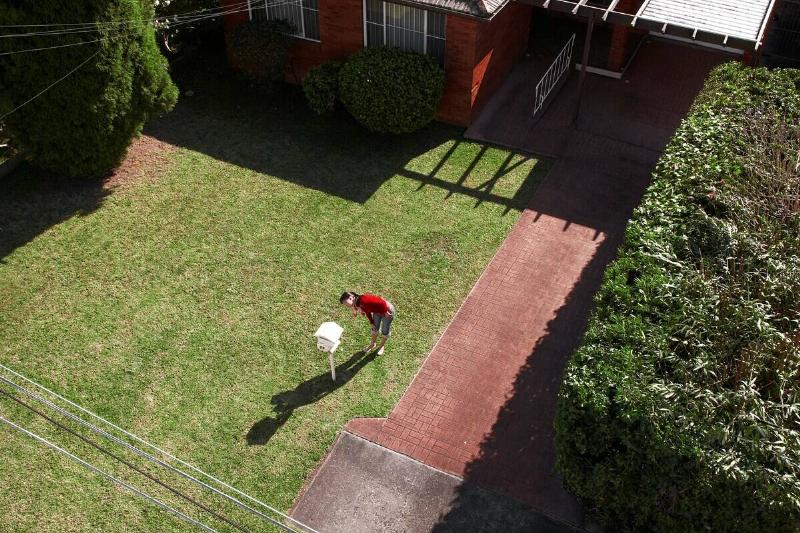 Aerial view of a person looking into their mailbox, which is in their front yard